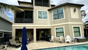 A two-story house with a swimming pool, outdoor furniture, and a balcony.