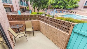 A patio area with a table and chairs, a pool in the background, and a blue gate.