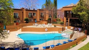 A residential building with a swimming pool, outdoor seating, and a fenced patio area.