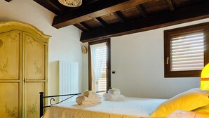 A bedroom with a bed, a wooden wardrobe, a window with blinds, and a bedside table. - Rustic  Cottage by Gran Sasso: Steps away from Amazing Hiking Trails (Frascara)