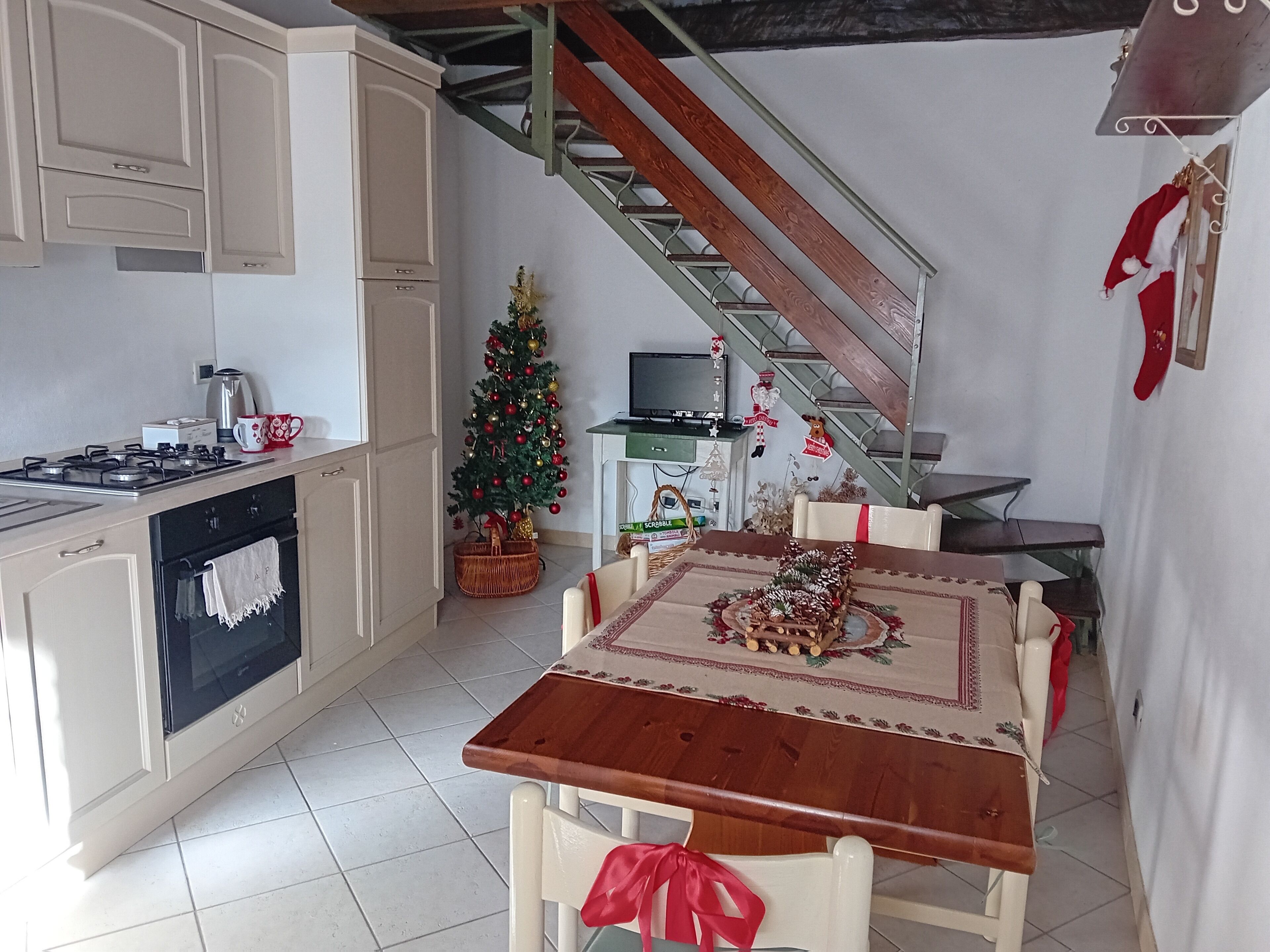 Una cocina con una mesa de comedor, un árbol de Navidad y una escalera.