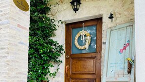 A rustic wooden door with a wreath, a stone wall, and a potted plant. - Rustic  Cottage by Gran Sasso: Steps away from Amazing Hiking Trails (Frascara)