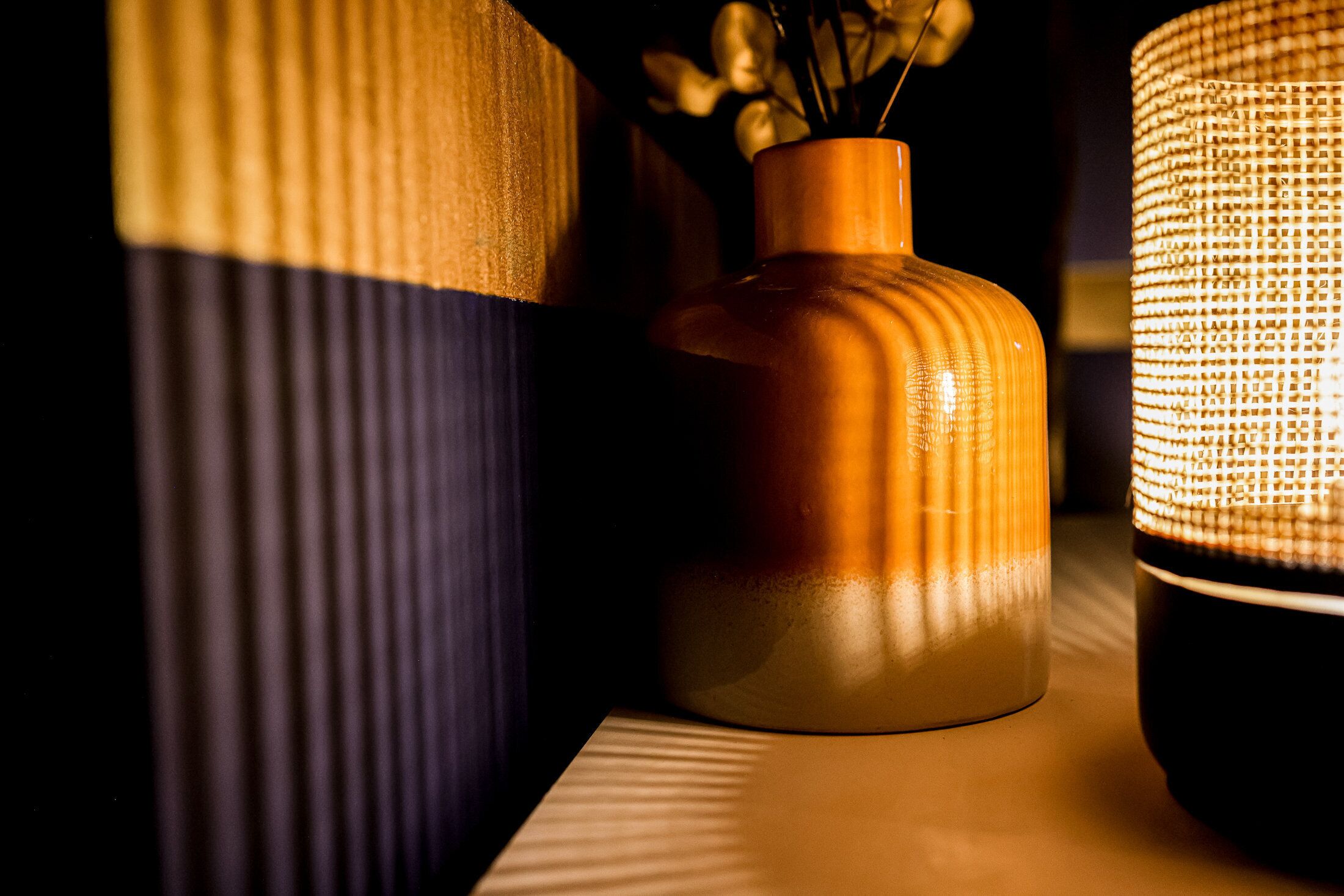 A close-up of three cylindrical vases with varying textures and a woven basket.