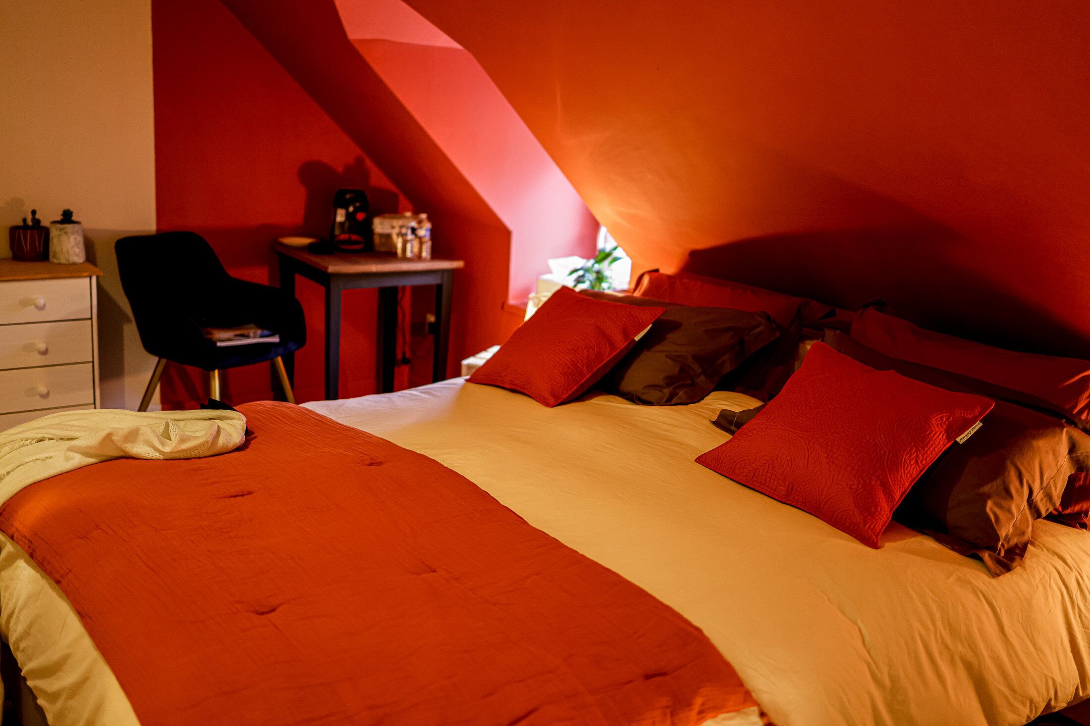 Una camera da letto con un letto, cuscini, una scrivania e una sedia.