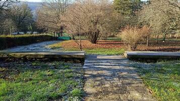 A pathway leading through a park with trees and a distant view of hills.