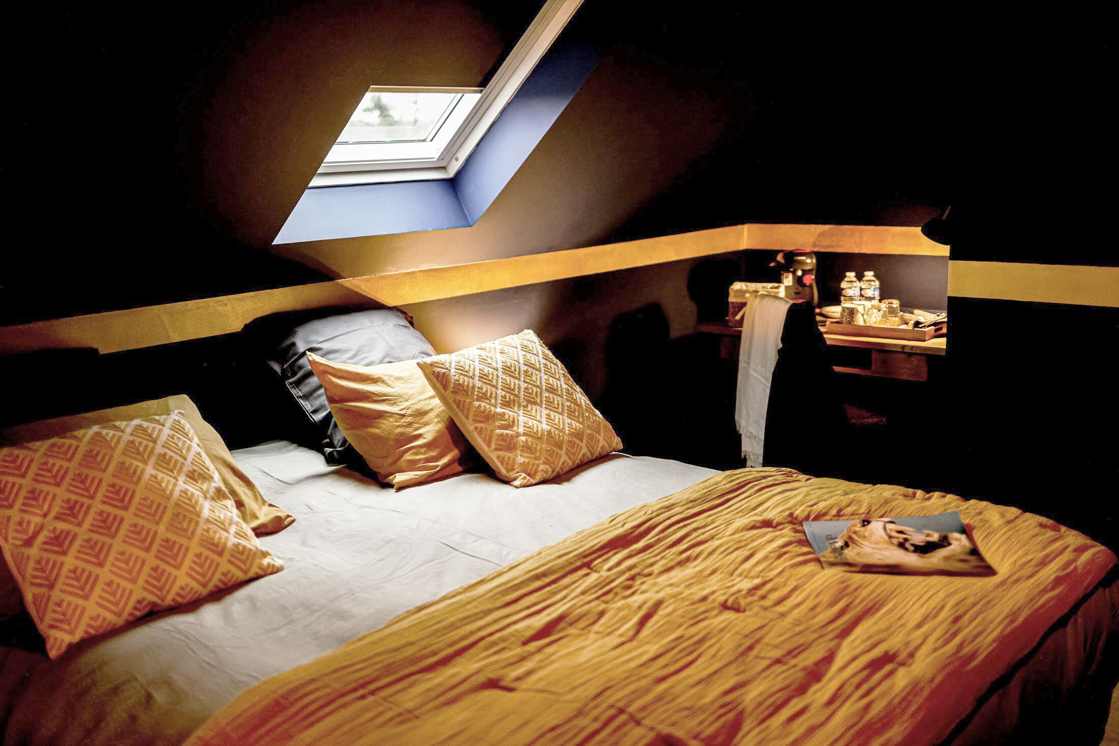 A bedroom with a bunk bed, a skylight, and a bedside table with items.