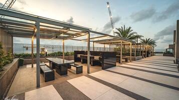 A rooftop terrace with outdoor seating and a view of the sea.