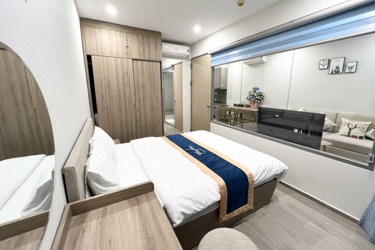 A modern hotel room with a bed, a desk, and a large mirror.