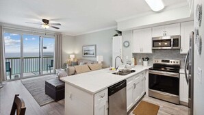 Una cocina moderna con una isla central, electrodomésticos de acero inoxidable y vistas al exterior.