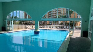 Una piscina interior con paredes de vidrio transparente, suelo de baldosas y un cartel de 'KEEP OFF'.