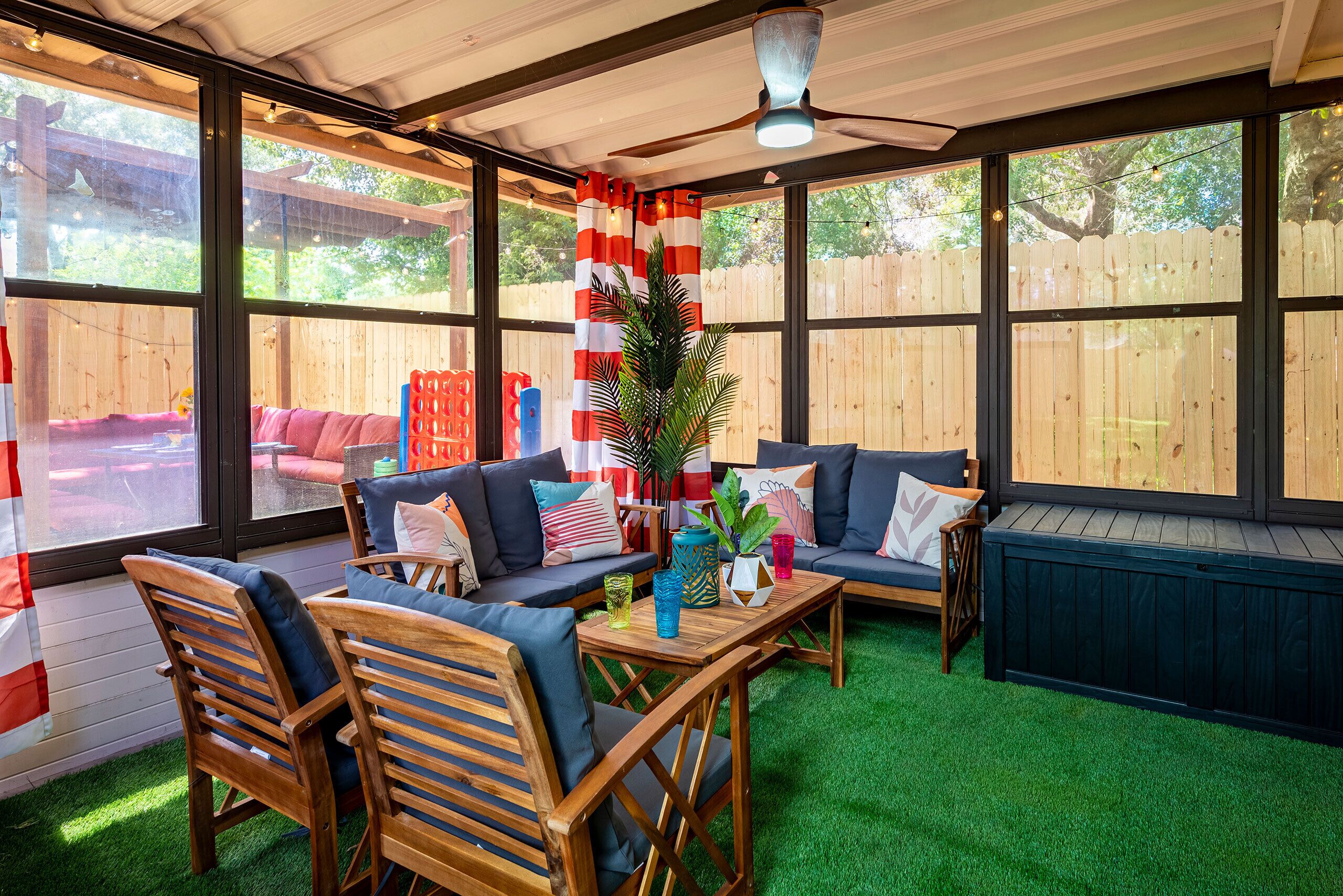 A covered patio with wooden furniture, a ceiling fan, and a view of a wooden fence.
