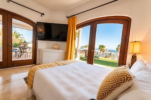Une chambre dâhĂŽtel avec un lit, une tĂ©lĂ©vision, une vue sur lâocĂ©an et un balcon amĂ©nagĂ© avec du mobilier dâextĂ©rieur.
