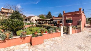 Un patio con suelo de piedra, plantas en macetas y una pequeña fuente.