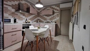 Cocina compacta con comedor, que incluye microondas, estufa, fregadero y una lámpara colgante.