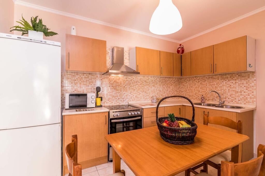 A compact kitchen with wooden cabinets, a microwave, an oven, and a dining table with chairs.