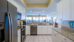 A kitchen with white cabinets, a stainless steel refrigerator, a dishwasher, and a granite countertop. -  "Miles-of-Smiles"- Navarre Beach Regency #611 (Navarre)