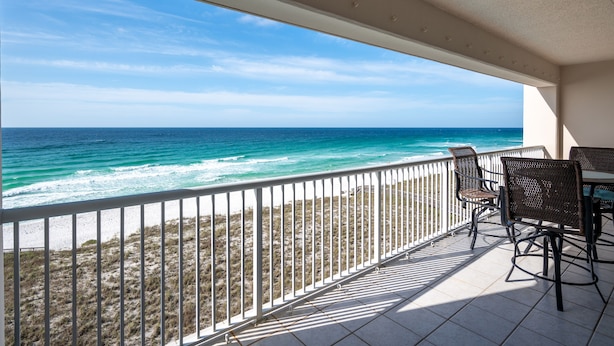 A balcony with a view of the ocean, white railings, and wicker chairs. -  "Miles-of-Smiles"- Navarre Beach Regency #611 (Navarre)