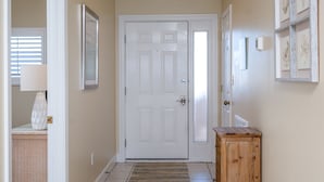 A hallway with a tiled floor, a wooden cabinet, and a door at the end. -  "Miles-of-Smiles"- Navarre Beach Regency #611 (Navarre)
