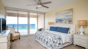 A bedroom with a bed, a TV, a chair, a nightstand, and a view of the ocean. -  "Miles-of-Smiles"- Navarre Beach Regency #611 (Navarre)