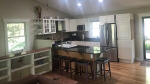 Una cocina moderna con armarios blancos, un refrigerador de acero inoxidable, un microondas y un ventilador de techo.
