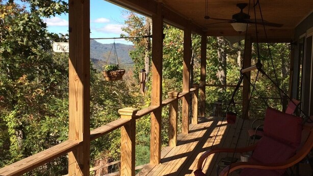 Una terraza de madera con una silla colgante y una cesta suspendida.