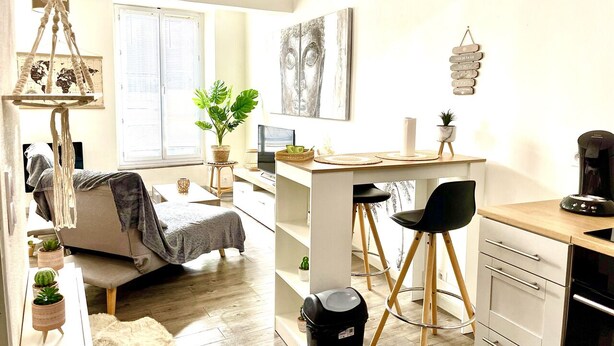 Un espace de vie compact comprenant un lit, une kitchenette, un coin repas et un petit bureau.