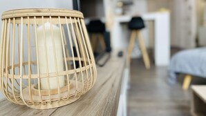 Un porte-bougie en bois, posé sur une table en bois dans une pièce moderne, avec un lit et un bureau en arrière-plan.