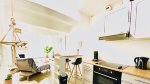 Une cuisine compacte dotée d’un îlot central, d’un coin repas avec un canapé et des chaises, et d’un luminaire suspendu.