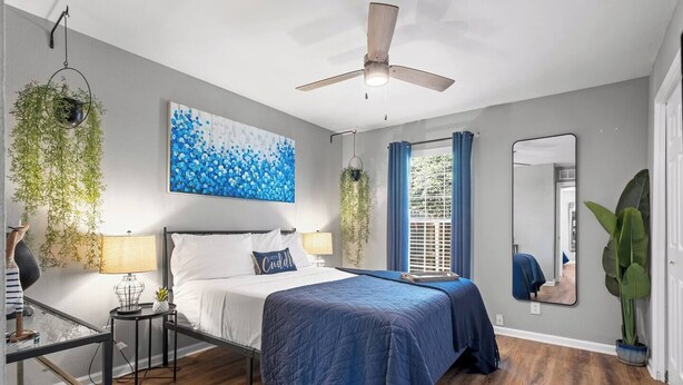 A bedroom with a bed, bedside tables, a ceiling fan, a large window with curtains, and a mirror. - 2 Bed w/ Fenced Yard * Dog Friendly * Fox Den E (Pensacola)