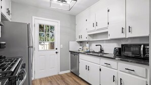 A modern kitchen with white cabinets, a black microwave, and a stainless steel refrigerator. - 2 Bed w/ Fenced Yard * Dog Friendly * Fox Den E (Pensacola)