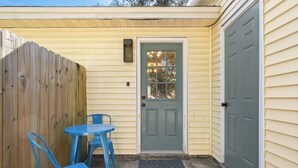 A small outdoor area with a wooden fence, a blue door, and a blue table with two chairs. - 2 Bed w/ Fenced Yard * Dog Friendly * Fox Den E (Pensacola)