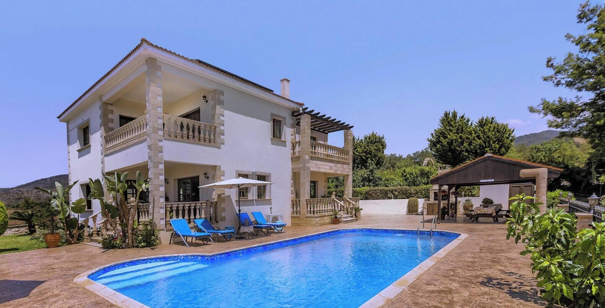 A two-story building with a pool, outdoor seating, and a pergola.