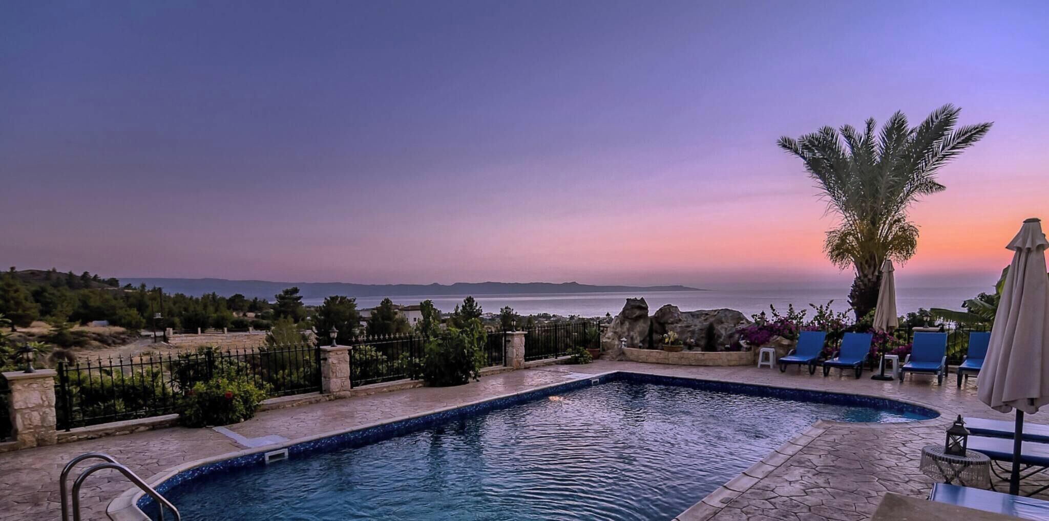 Une piscine avec vue sur la mer et sur le coucher de soleil.