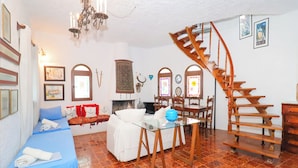 Um quarto com cama, mesa de jantar, cadeiras, lareira e uma escada em espiral.