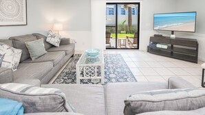 A living room with a grey sofa, a coffee table, and a TV on a stand.