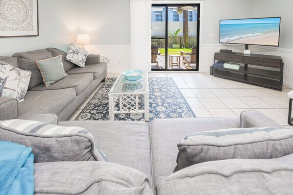 A living room with a grey sofa, a coffee table, and a TV on a stand.