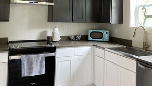 A modern kitchen with dark cabinets, a stainless steel range, a microwave, and a window with a view. - Gorgeous beach view, private balcony suites (Biloxi)