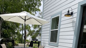 A wooden deck with a table and chairs, a white umbrella, and a small toy car on a railing. - Gorgeous beach view, private balcony suites (Biloxi)