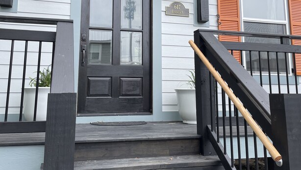 A front view of a house with a black front door, white siding, and a number "647" sign. - Gorgeous beach view, private balcony suites (Biloxi)