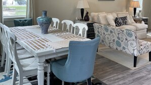 A dining area with a chandelier, a table with a patterned table runner, and a blue chair. - Gorgeous beach view, private balcony suites (Biloxi)