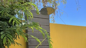 A modern outdoor area with a wooden wall, a metal door, and lush greenery.