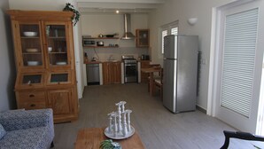 A modern kitchen with wooden cabinets, a refrigerator, and a dining area with a table and chairs.