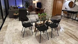 A modern living room with a glass dining table, black mesh chairs, and a stone accent wall. - Casa Montes de Amé, gran ubicación y comodidad (Mérida)