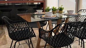A modern kitchen with wooden cabinets, a glass dining table, black chairs, and pendant lights. - Casa Montes de Amé, gran ubicación y comodidad (Mérida)