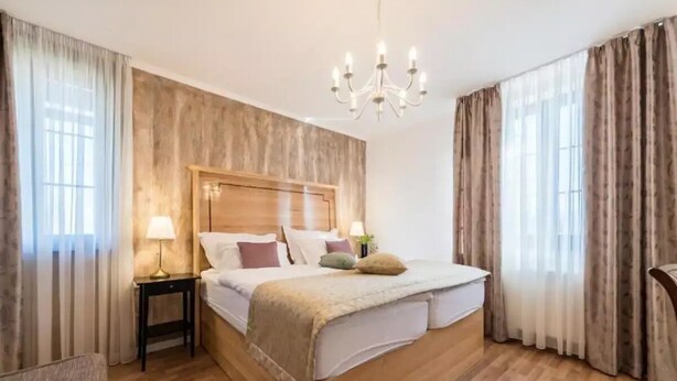 A bedroom with a wooden bed, a nightstand, a lamp, and a chandelier.