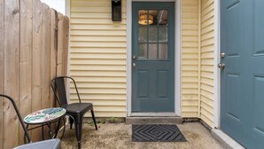 A house with a blue door, a small porch with a chair, and a wooden fence.