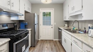 A modern kitchen with white cabinets, a stainless steel refrigerator, a gas stove, and a dishwasher.