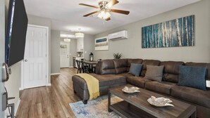 A living room with a sectional sofa, a coffee table, and a ceiling fan.