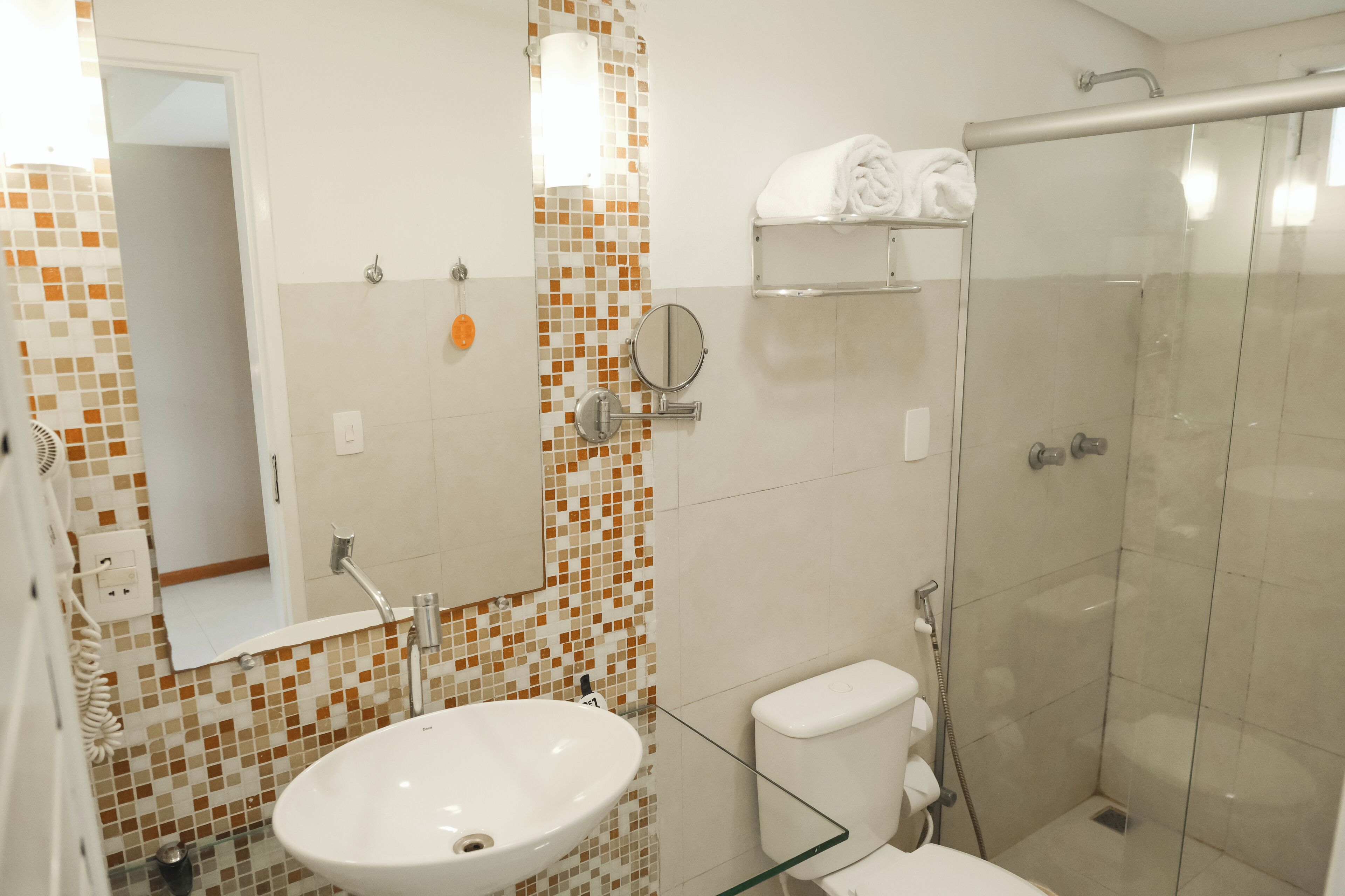 A bathroom with a glass shower enclosure, a white sink, and a toilet.