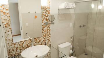 A bathroom with a glass shower enclosure, a white sink, and a toilet.